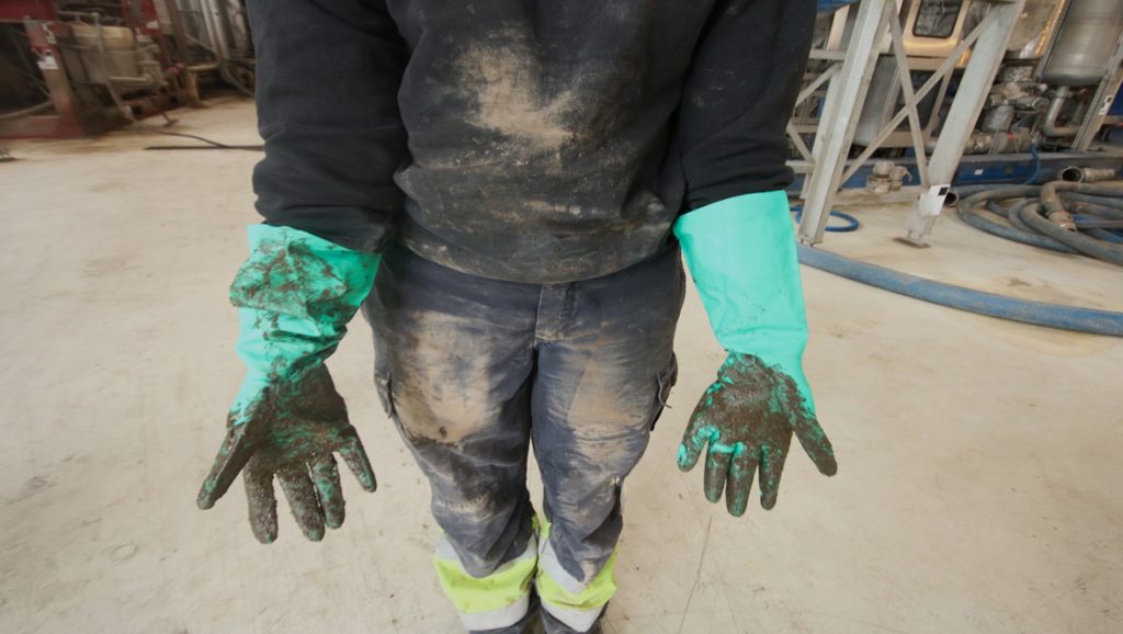 Bilde av person med hansker og iført olje.
