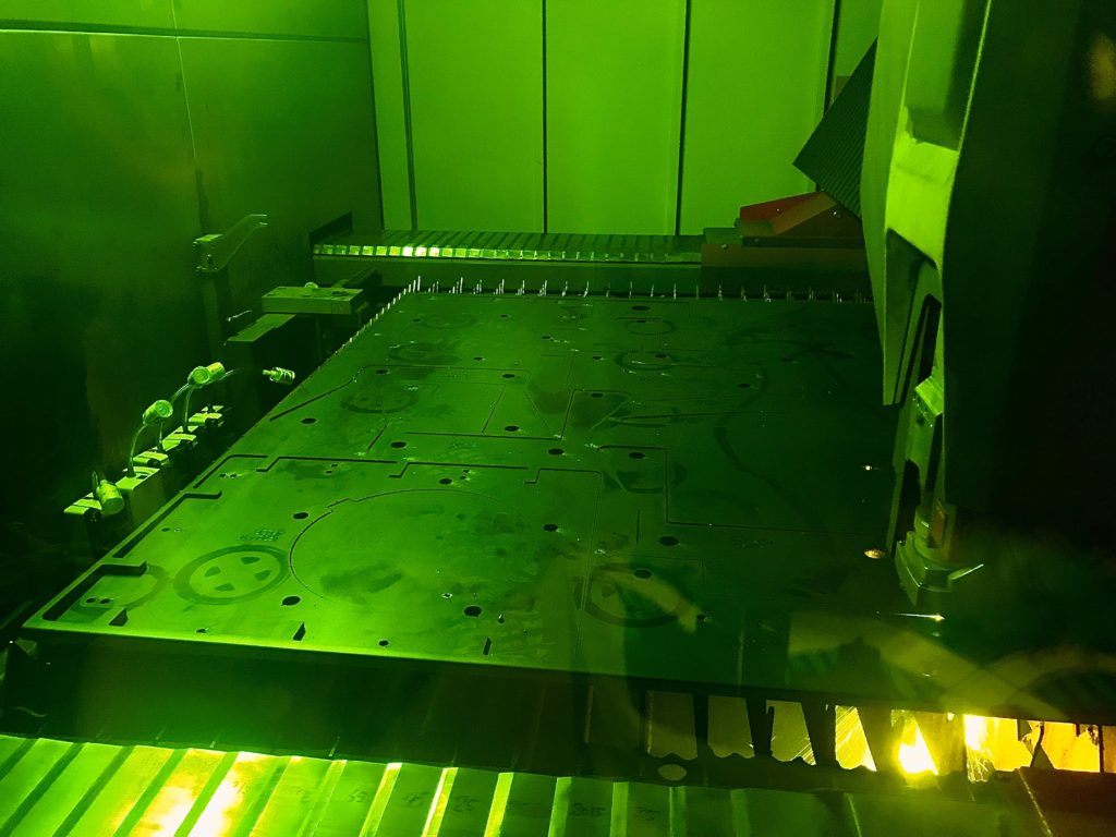 Laser som skjærer i metallplate, grønt lys.