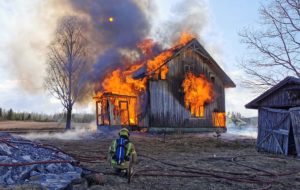 Brannkonstabel framfor hus som brenner
