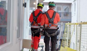 To bygningsarbeidere i arbedsklær og sikkerhetssele på byggeplass