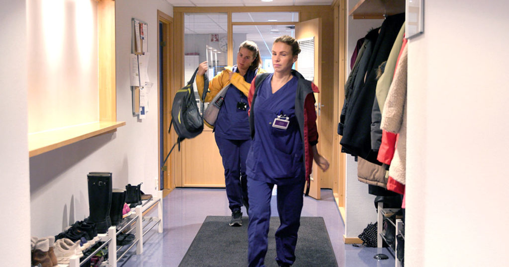 To hjemmesykepleiere i sykepleierklær på vei ut av kontoret på oppdrag.