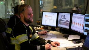 Ein tilsett arbeider framfor fleire skjermar i eit kontrollrom i eit industrilokale