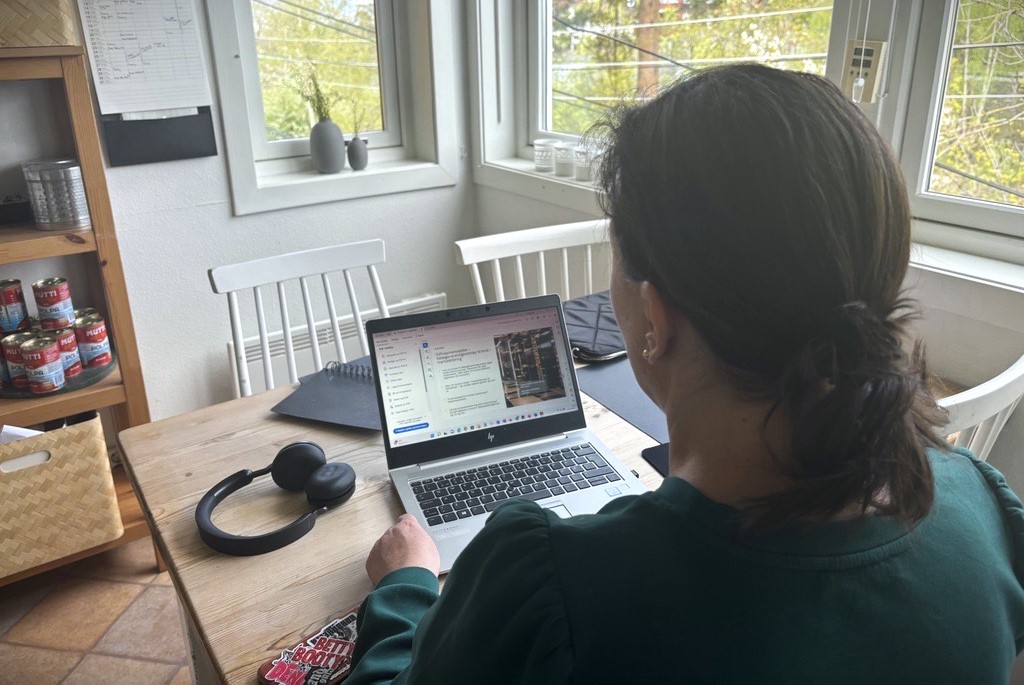 Kvinne arbeider med bærbar PC ved kjøkkenbord