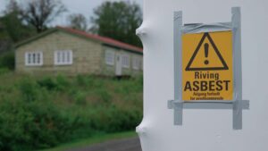 Varselskilt som advarer mot asbest – brukt for å informere om helsefarlig materiale på et saneringsområde.