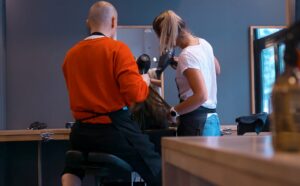 To frisører av ulik kjønn i arbeid med kunde.