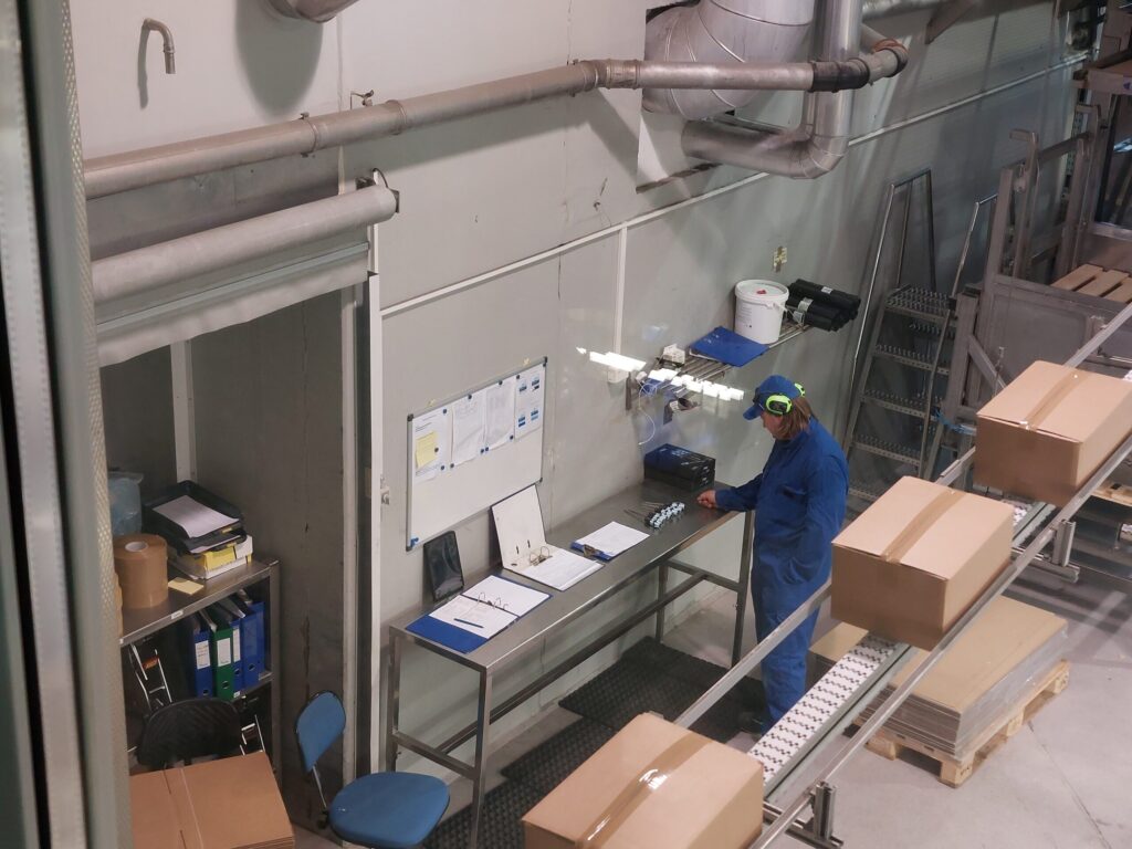 Ansatt på rekefabrikk kontrollerer linje med pakkede produkter.