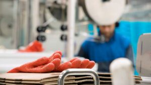 Et par fiskerihansker på en stabel, med en ansatt i bakgrunnen