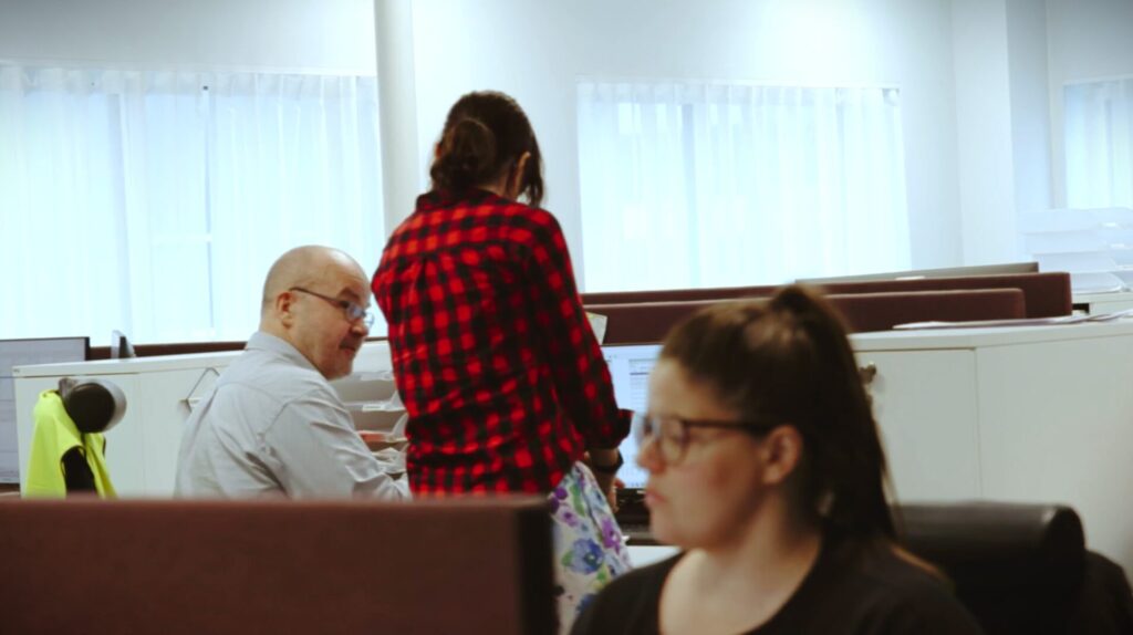 to personer snakker sammen ved en pult i et kontorlandskap