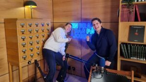 Anne-Mette Aasheim fra Fornybar Norge sammen med programleder Daniel Kolbeinshavn. Peker fornøyd mot et lysende skilt hvor det står "En bra dag på jobb".