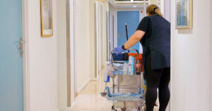 Renholder med en utstyrstralle i en korridor