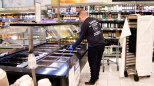 Ung mann i dagligvarebutikk som rydder i salatbaren.