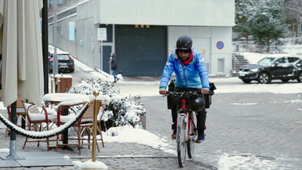sykkelbud sykler i snødekt bymiljø